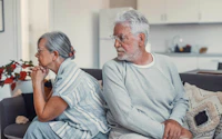 Divorce senior woman and fight or sad in marriage in living room with partner or angry in home problem upset and female person with conflict on sofa with couple or breakup and frustrated together 2716777885